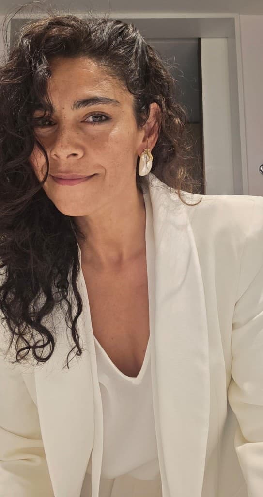 Sarah Angelo, founder of The Better Man Project, in a white blazer with a warm, confident smile
